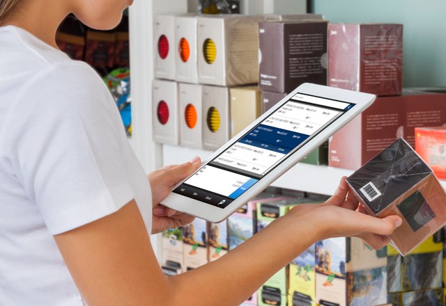 a sales woman viewing stock - inventory of a certain box of teas using a mobile POS tablet