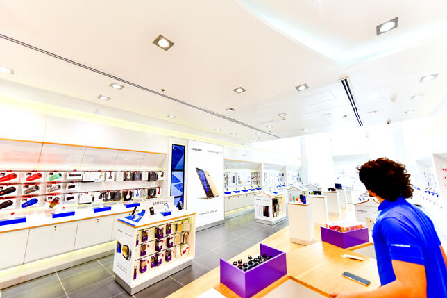 Retailer in a blue shirt in clean Al-Hadad store with lots of white surfaces