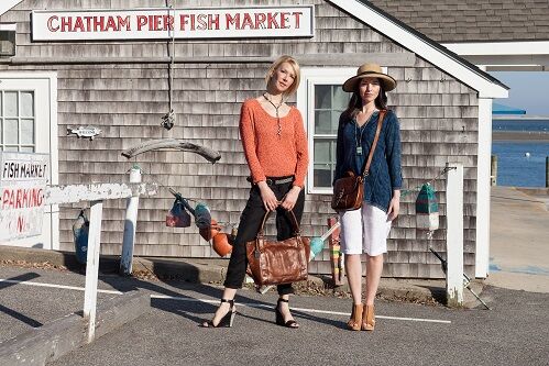 One blonde and one brunette women modeling clothes outside of 'CHATHAM PIER FISH MARKET'