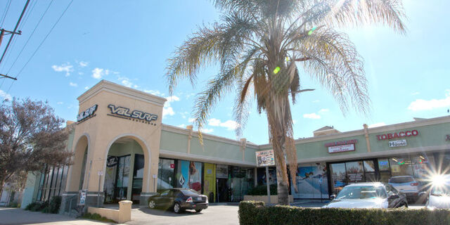 Southern-California style storefront seen outside from an angle with palm trees littered around