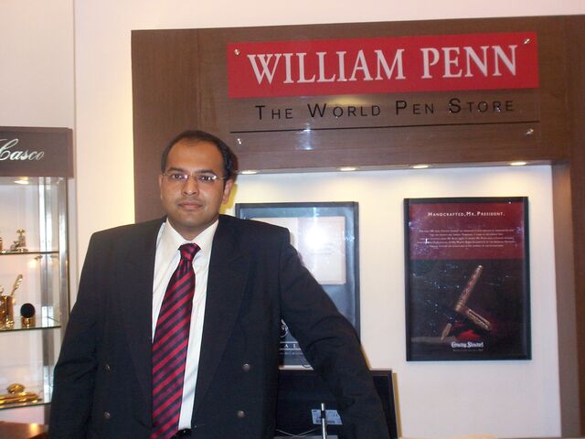 Cleanshaven Indian man in business suit standing inside store