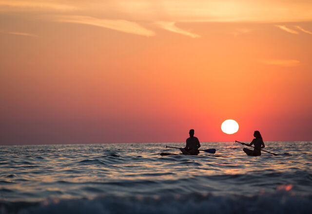 Man and woman paddling into the sunset