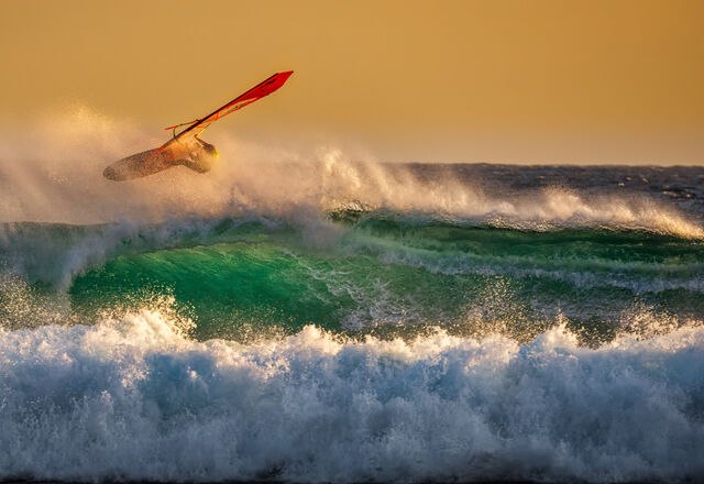 Man riding a wave while kite surfing