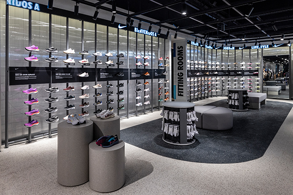 Inside a Nike store, showing a wall of shoes on display for sale