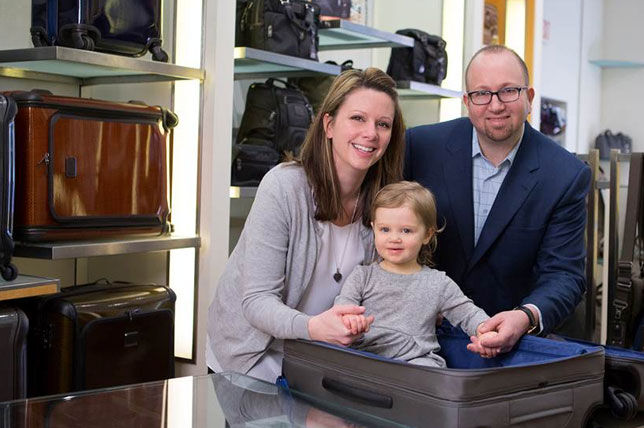 Family with a cute baby sitting in a nice suitcase
