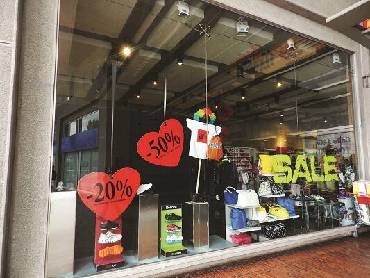 Exterior of a retail store with -20% and -50% 'SALE' signs placed on hearts in the window