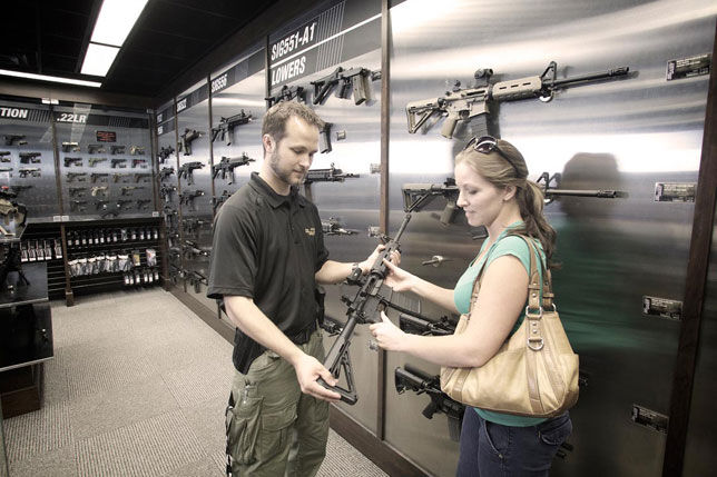 Woman being shown a rifle.