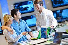 retailer showing off laptop to two consumers